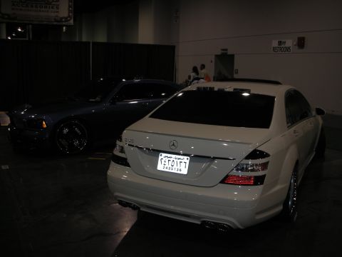 1998 Ford Crown Victoria - Two luxury sedans are parked indoors, one white and one dark blue.