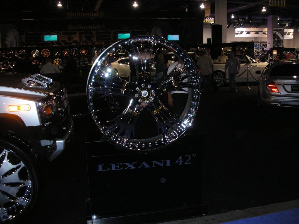 Lexani 42" chrome wheel on black stand, with part of a silver Hummer and a silver Mercedes-Benz visible