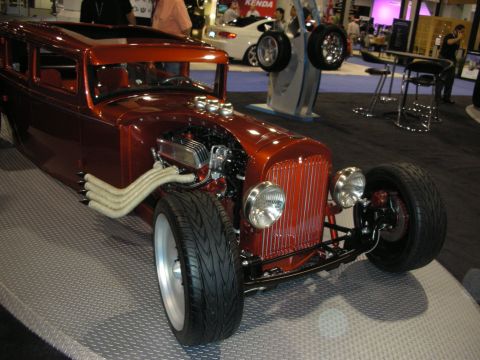 1998 Ford Crown Victoria - A custom hot rod with a prominent V8 engine and unique exhaust system is displayed indoors.