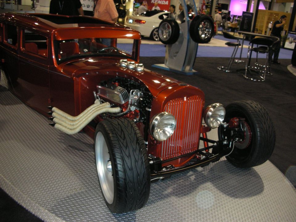 Orange hot rod with exposed engine, custom exhaust pipes, and sunroof