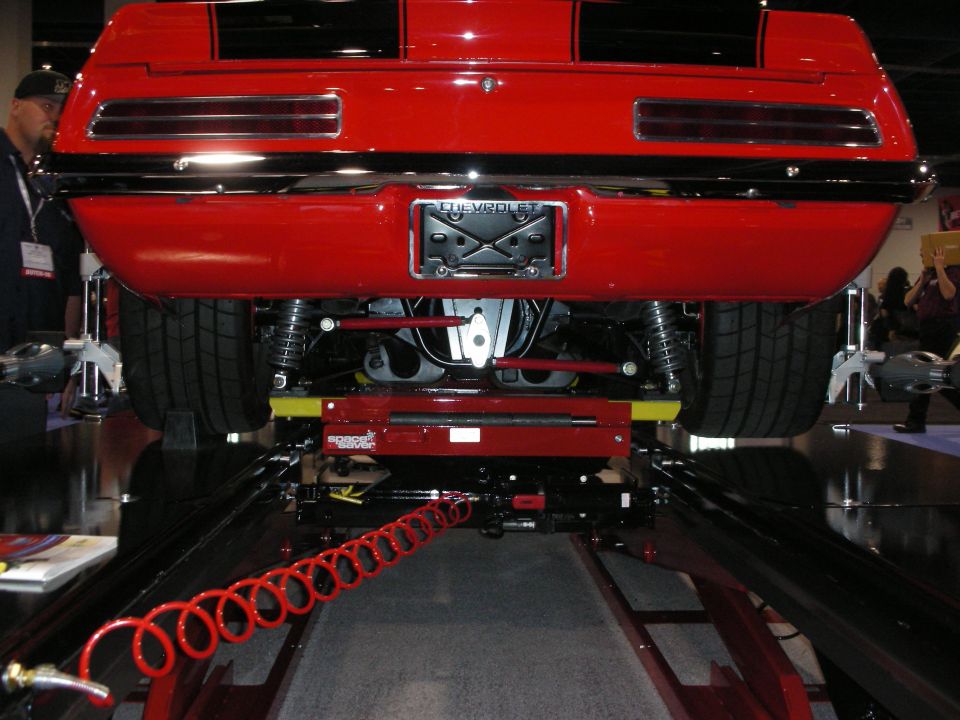 Red 1969 Chevrolet Camaro rear end with black stripes, on a lift. Chevrolet badge visible
