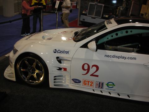 1998 Ford Crown Victoria - A white race car with various sponsor decals is displayed indoors.
