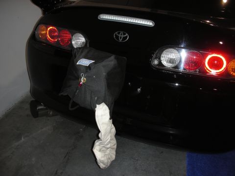 1998 Ford Crown Victoria - The rear of a black Toyota Supra is shown with a black bag hanging from the bumper.