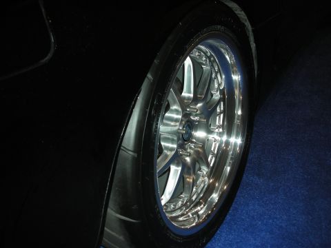 1998 Ford Crown Victoria - Close-up of a black vehicle's rear wheel a custom chrome multi-spoke rim and low-profile tire.
