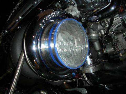 1998 Ford Crown Victoria - A shiny turbocharger with a mesh screen is visible, surrounded by engine components.