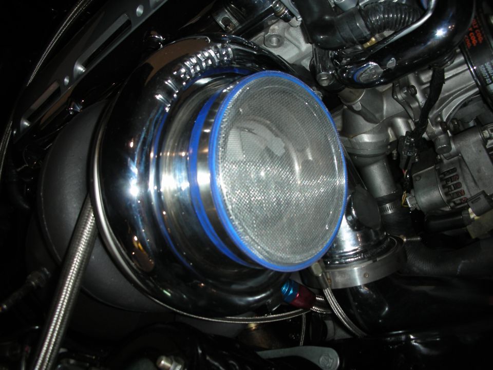Close-up of a chrome turbocharger with blue trim and a mesh intake