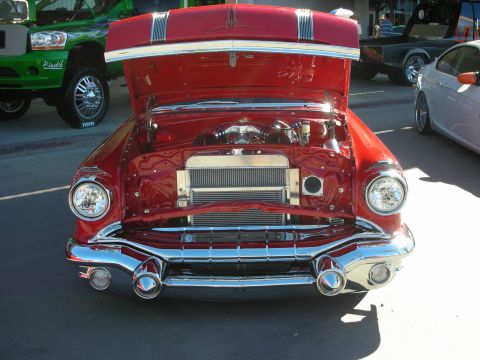 1998 Ford Crown Victoria - A red classic car is parked outside with its hood open, revealing the engine compartment.