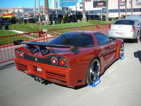 1998 Ford Crown Victoria - A heavily modified red sports car is displayed outdoors, with another vehicle visible in the background.