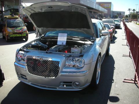 1998 Ford Crown Victoria - A silver Chrysler 300 is displayed with its hood open, revealing the engine bay and prominent front grille.