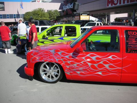 1998 Ford Crown Victoria - Customized pickup trucks with flame graphics displayed at an outdoor event.