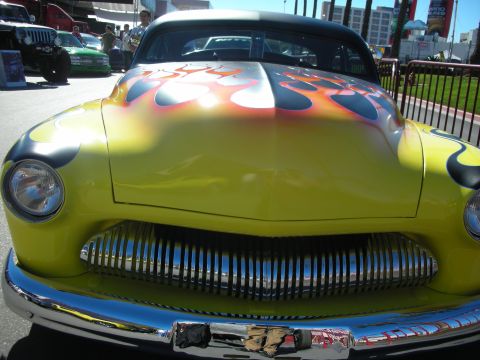 1998 Ford Crown Victoria - A yellow hot rod with flame decals is parked outdoors, with other vehicles and buildings in the background.