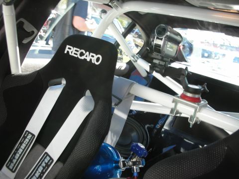 1998 Ford Crown Victoria - The interior of a modified vehicle features a racing seat, safety harness, and a camera for recording track activity.