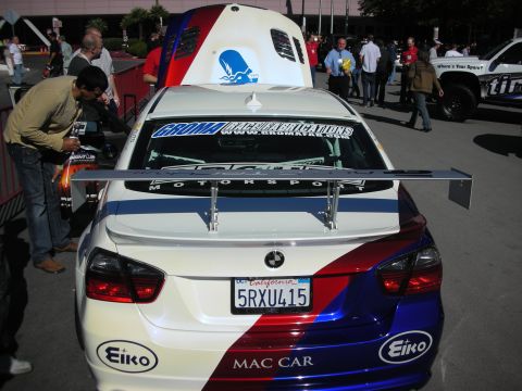 1998 Ford Crown Victoria - A white BMW with a distinctive red and blue racing livery and a large rear spoiler is displayed with its hood open.