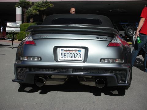 1998 Ford Crown Victoria - Rear view of a Nissan 350Z convertible, modified with Nismo parts and dual exhaust pipes.