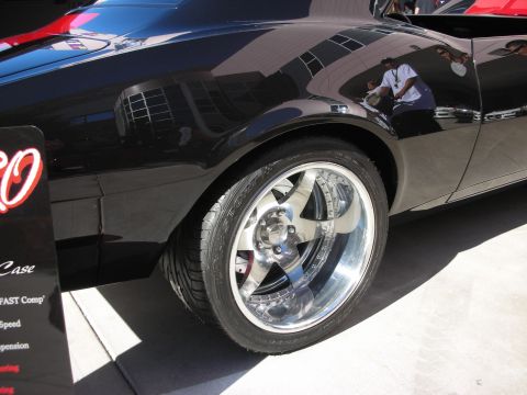 1998 Ford Crown Victoria - Close-up of a black car's side profile, highlighting its custom chrome wheels and tires.