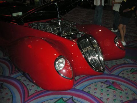 1998 Ford Crown Victoria - A custom red car with an exposed engine and unique front-end design is displayed indoors.