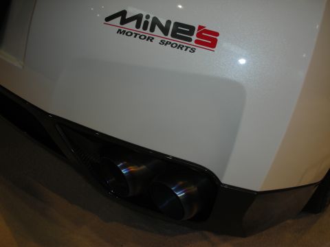 1998 Ford Crown Victoria - A white car's rear bumper displays dual exhaust pipes and the 'MiNES MOTOR SPORTS' logo.