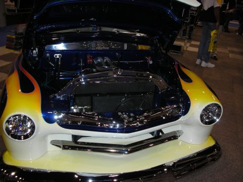 1998 Ford Crown Victoria - A customized hot rod with flame paint and chrome accents is displayed with its hood open.