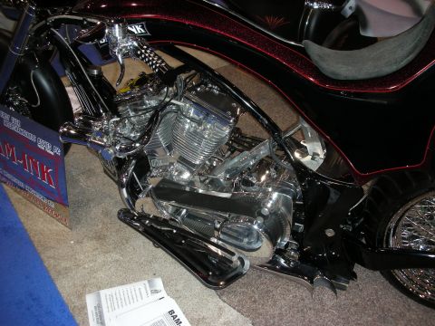1998 Ford Crown Victoria - A custom motorcycle with a prominent chrome engine is displayed indoors.