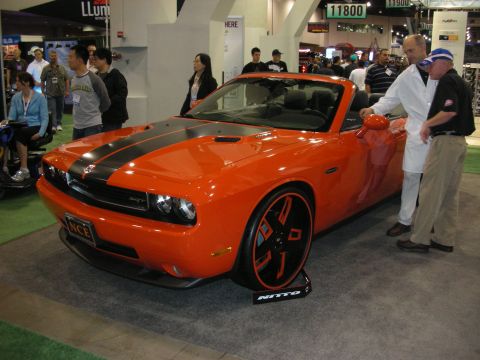 1998 Ford Crown Victoria - An orange convertible sports car with black racing stripes and custom wheels is on display at an event.