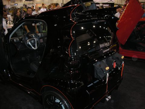 1998 Ford Crown Victoria - Modified black smart car with custom trim and doors displayed at an event.