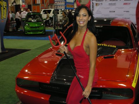 1998 Ford Crown Victoria - A woman in a devil costume poses with a red sports car at an event.