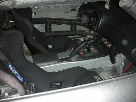 1998 Ford Crown Victoria - The interior of a modified vehicle features racing seats and a roll cage, with a view of the dashboard and gear shifter.