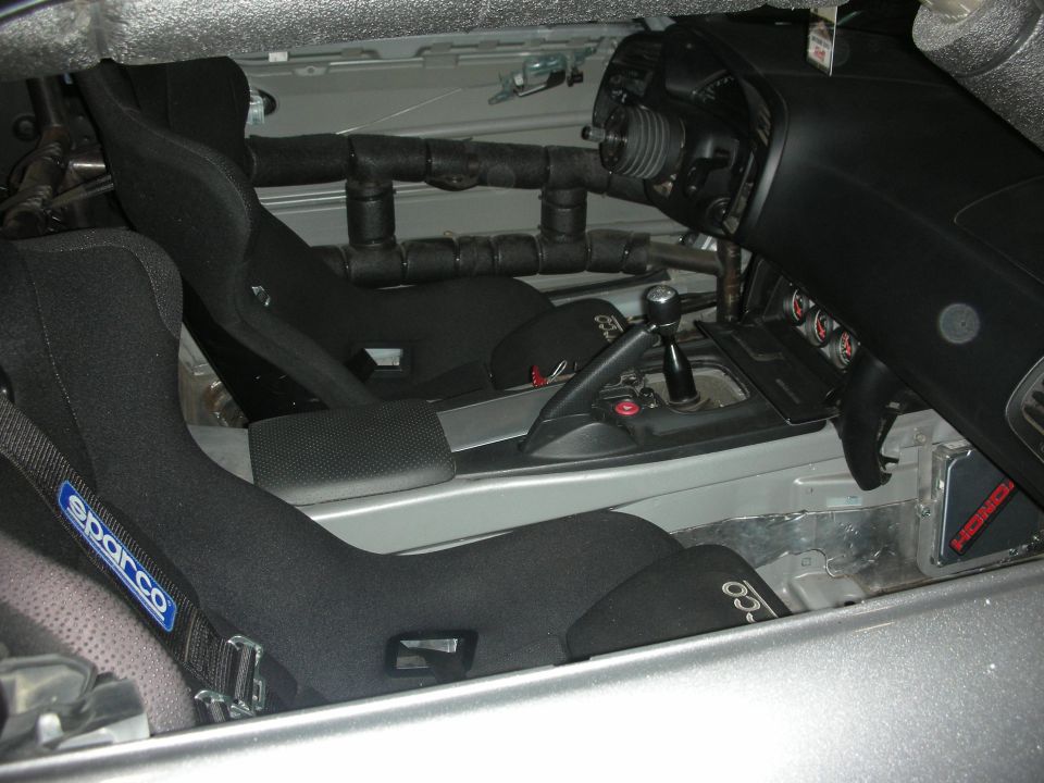 Interior shot of a car with racing seats, roll cage, and dashboard