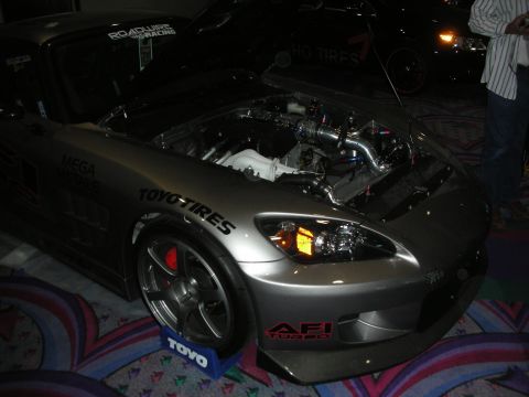 1998 Ford Crown Victoria - A silver sports car with its hood open, displaying its engine and various aftermarket modifications.