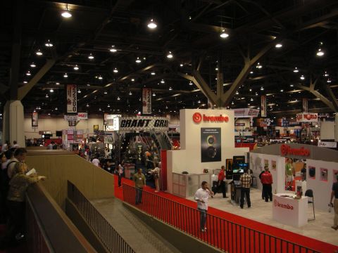 1998 Ford Crown Victoria - Busy scene inside a convention center with various automotive industry exhibits and attendees.