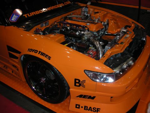 1998 Ford Crown Victoria - Customized orange sports car with engine exposed, aftermarket parts and prominent branding.
