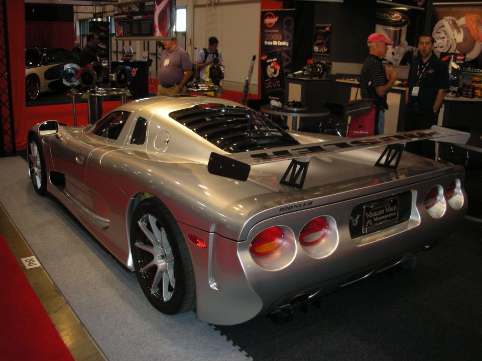 Silver Mosler sports car with a large rear wing, quad taillights, and custom wheels