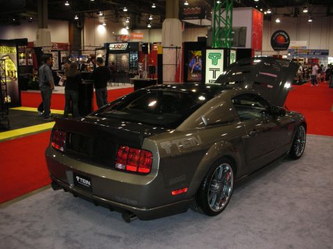 1998 Ford Crown Victoria - A modified Ford Mustang is displayed at an indoor event with its hood open.