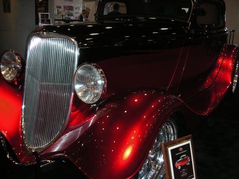 1998 Ford Crown Victoria - A close-up view of a custom hot rod, its metallic red paint and chrome grille.