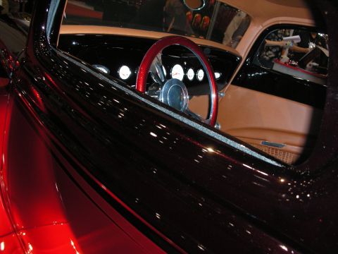 1998 Ford Crown Victoria - The interior of a custom hot rod features a shiny red steering wheel and tan upholstery.