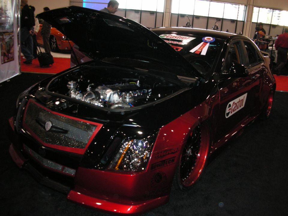 Customized black and red Cadillac CTS with hood open showing engine, Castrol decals on door