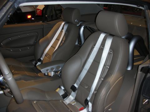 1998 Ford Crown Victoria - The interior of a car shows two bucket seats with racing harnesses and a roll bar.