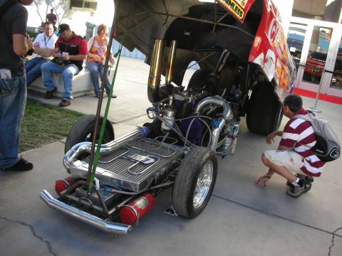 1998 Ford Crown Victoria - Exposed engine and chassis of a drag racing car, with a person observing the build.