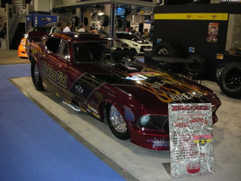 1998 Ford Crown Victoria - A custom drag car with extensive decals and a prominent engine is displayed indoors.