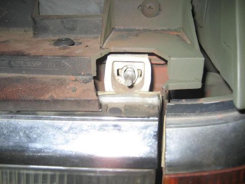 1987 Ford Bronco - Close-up of a headlight mounting bracket, showing the adjustment mechanism and text indicating 'HEADLAMP AIM'.