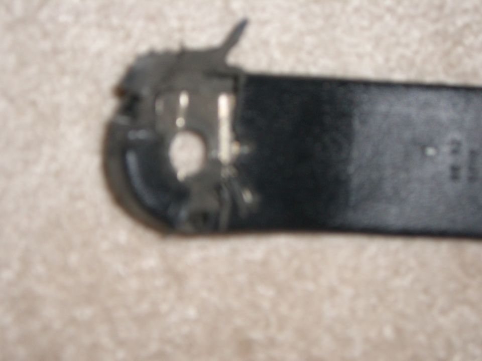 Black seatbelt buckle mechanism with metal components, on a carpeted surface