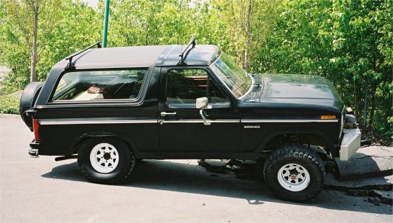 Black 1985 Ford Bronco side view with removable top and spare tire