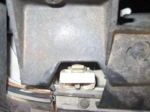 1987 Ford Bronco - Close-up of a vehicle's headlight mounting bracket, showing internal components and hardware.