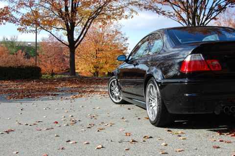2002 BMW M3 - A black BMW M3 is parked on a street covered in fallen leaves during autumn.