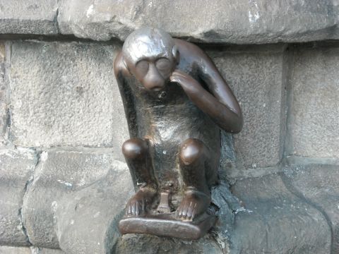 1979 Ford F-150 - A bronze sculpture of a monkey is affixed to a stone wall, appearing to contemplate its surroundings.