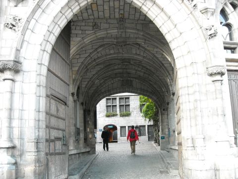 1979 Ford F-150 - A view through a large stone archway onto a cobblestone street with two pedestrians.