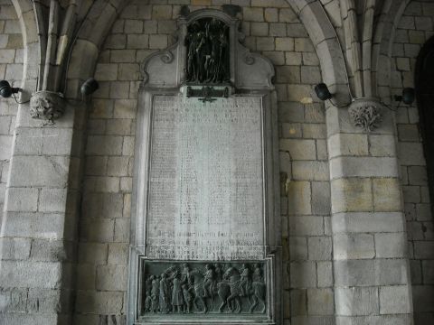 1979 Ford F-150 - A large, ornate war memorial plaque is mounted on a stone wall, lists of names and a detailed relief sculpture at the bottom.