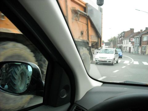 1979 Ford F-150 - A large dump truck is seen from the driver's perspective, with other vehicles and buildings visible on the street.