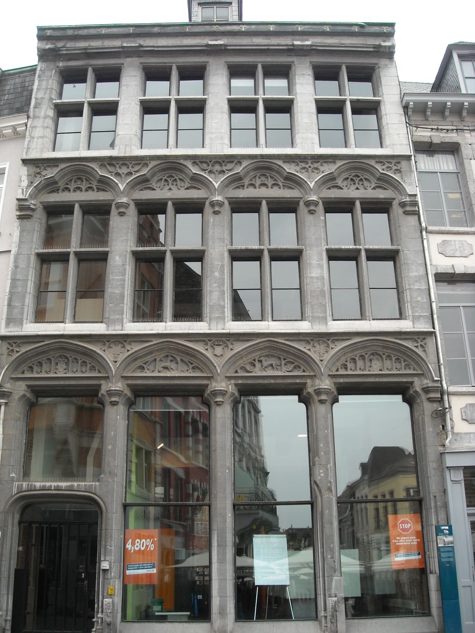 Stone building facade with ornate windows and reflections of street scene