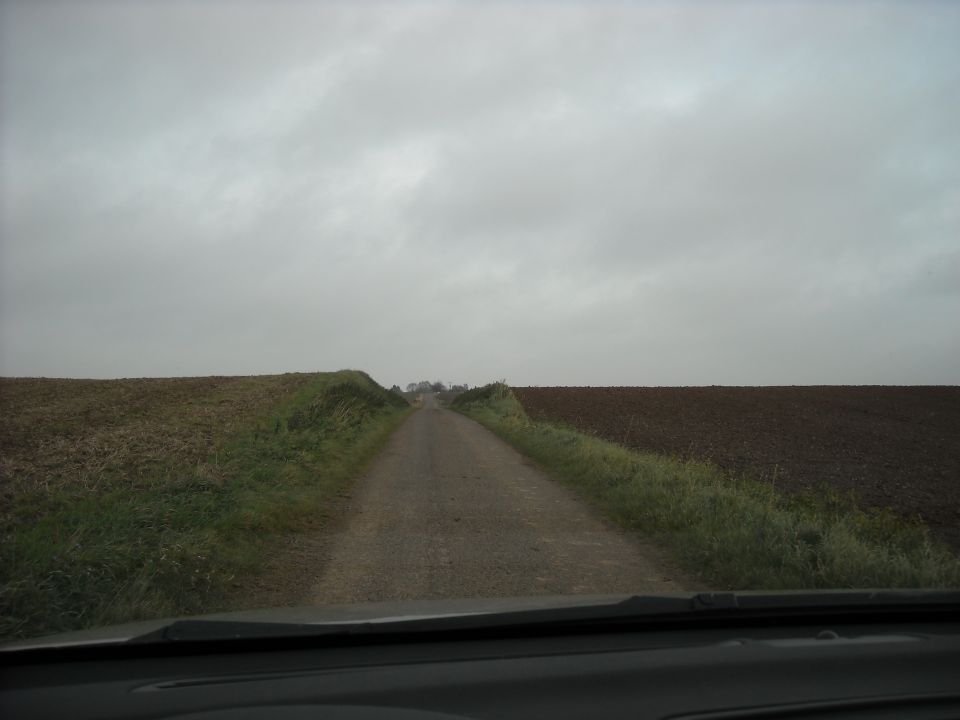 Dashboard view of a rural road under a cloudy sky